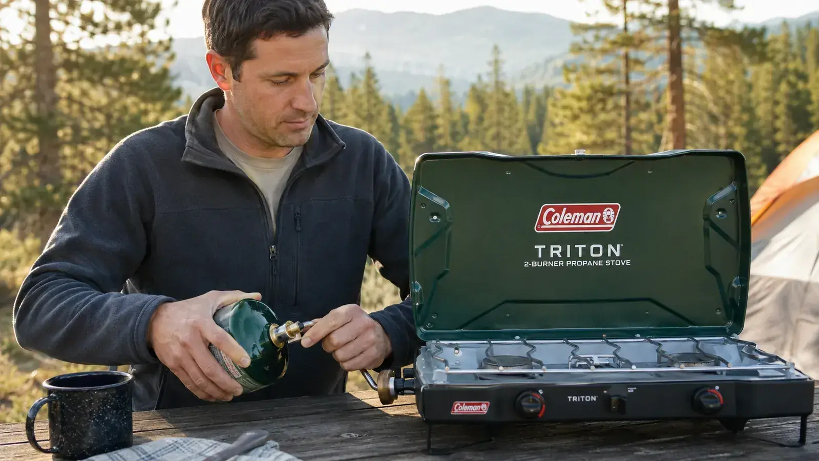 Hands connecting a propane canister hose to the Coleman Triton stove regulator outdoors